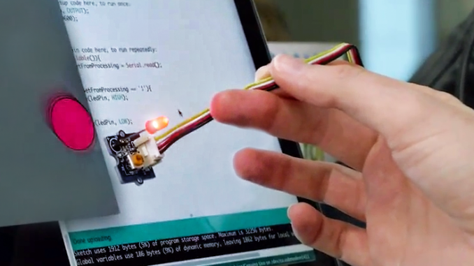 A hand holding a lighted stylus that is programmed by a computer